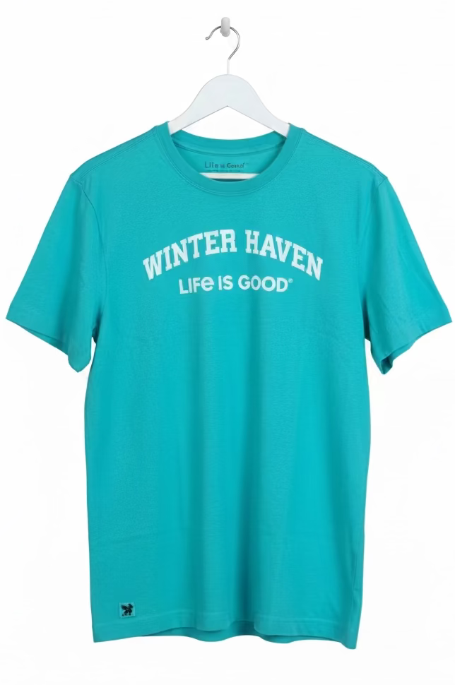 Turquoise t-shirt with 'Winter Haven Life is Good' text on a hanger in a store setting.