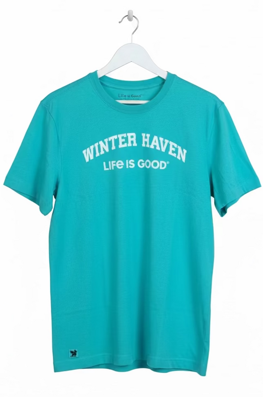 Turquoise t-shirt with 'Winter Haven Life is Good' text on a hanger in a store setting.